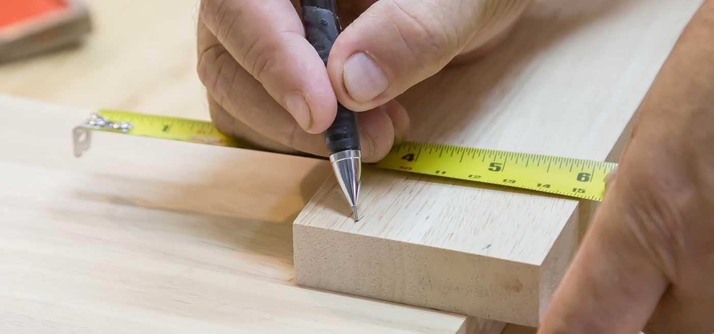 Carpenter Measuring Wood Prior To Cutting